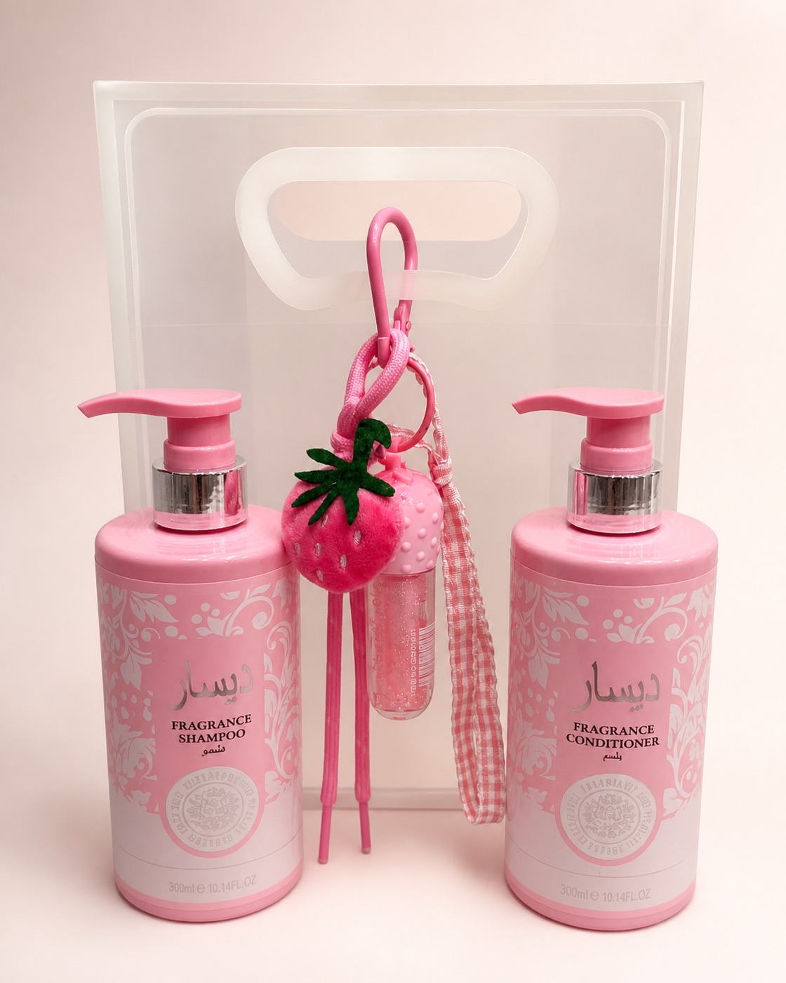 Un kit de Cositas Lindas armado: shampoo y acondicionador en rosa, un llavero de fresa con gloss y su bolsa de regalo.